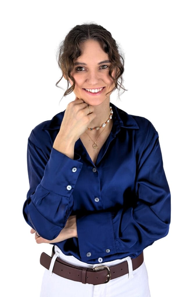 Uśmiechnięta mgr Kalina Paszyna-Grochowska, psycholog i założycielka Portalu PsychologNaFali, w portretowym ujęciu z dłonią pod brodą, ubrana w granatową satynową koszulę oraz białe spodnie z brązowym paskiem – oferująca wsparcie i konsultacje psychologiczne dla młodzieży i dorosłych.